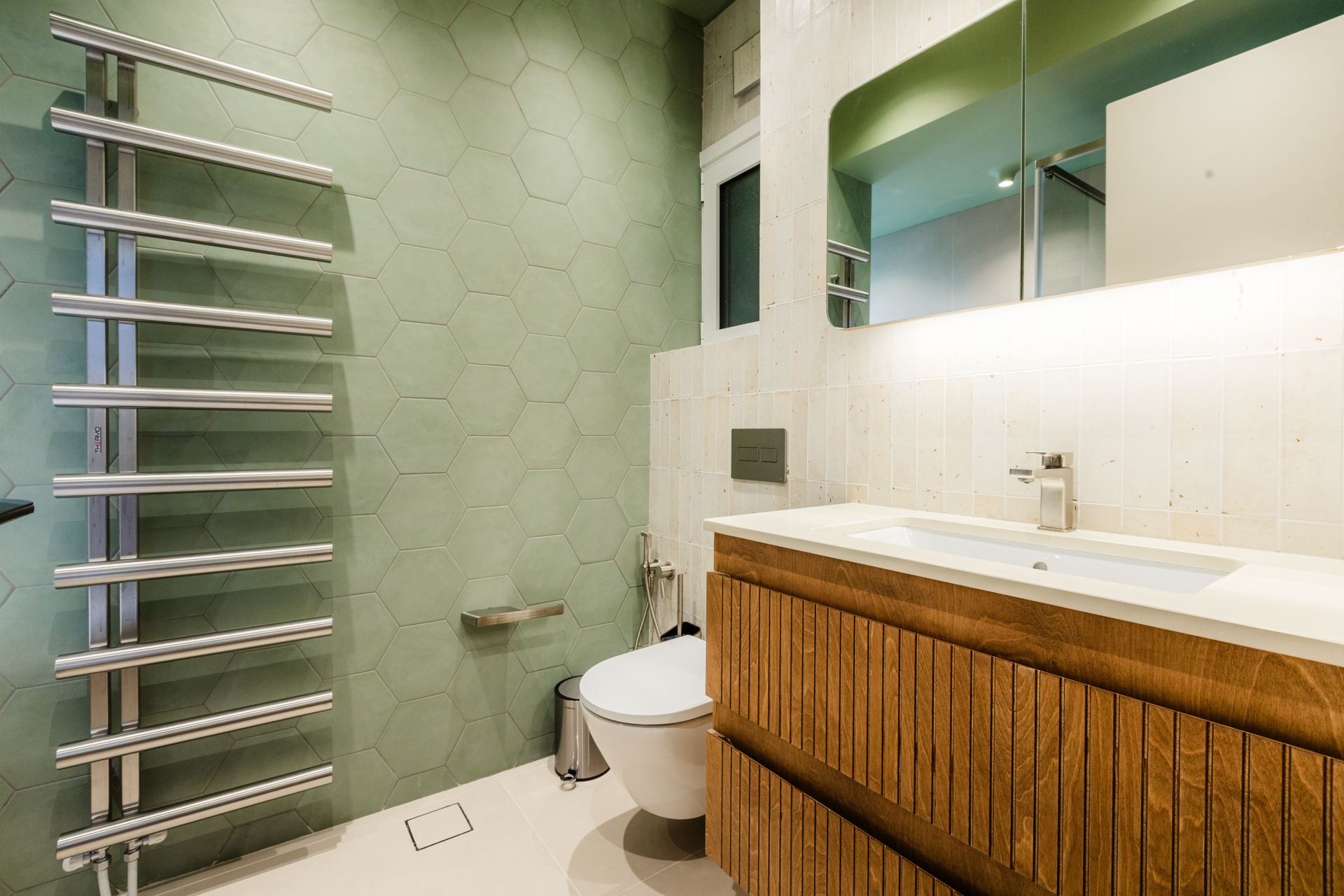 Μοντέρνο μπάνιο με ντουζιέρα και μπανιέρα Πράσινα εξαγωνικά πλακάκια μπάνιου Ξύλινο έπιπλο μπάνιου με fluted λεπτομέρειες Μπλε πλακάκια τοίχου μπάνιου Εντοιχισμένο καζανάκι και κρεμαστή λεκάνη Μοντέρνα καμπίνα ντους με διάφανο κρύσταλλο