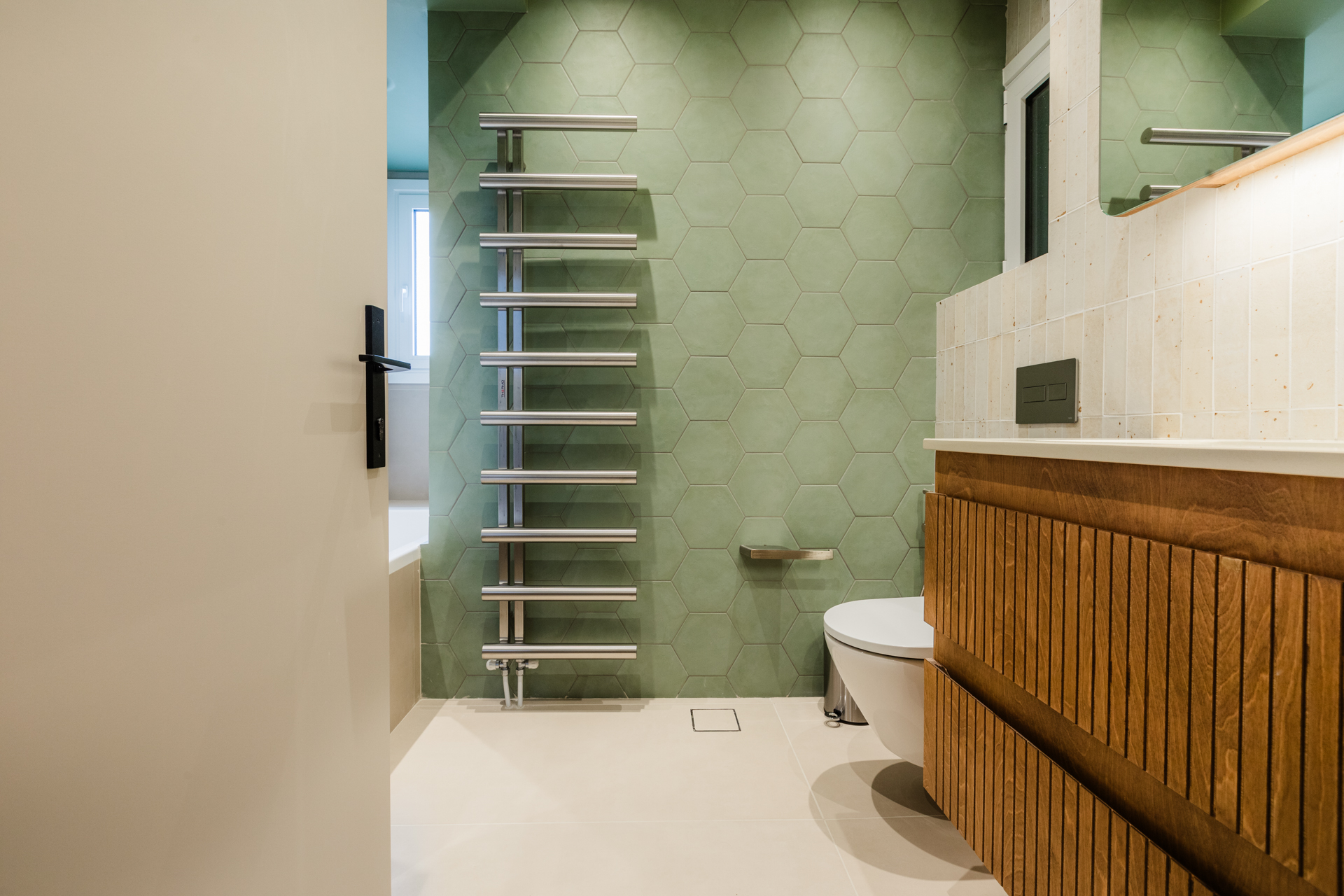 Μοντέρνο μπάνιο με ντουζιέρα και μπανιέρα Πράσινα εξαγωνικά πλακάκια μπάνιου Ξύλινο έπιπλο μπάνιου με fluted λεπτομέρειες Μπλε πλακάκια τοίχου μπάνιου Εντοιχισμένο καζανάκι και κρεμαστή λεκάνη Μοντέρνα καμπίνα ντους με διάφανο κρύσταλλο