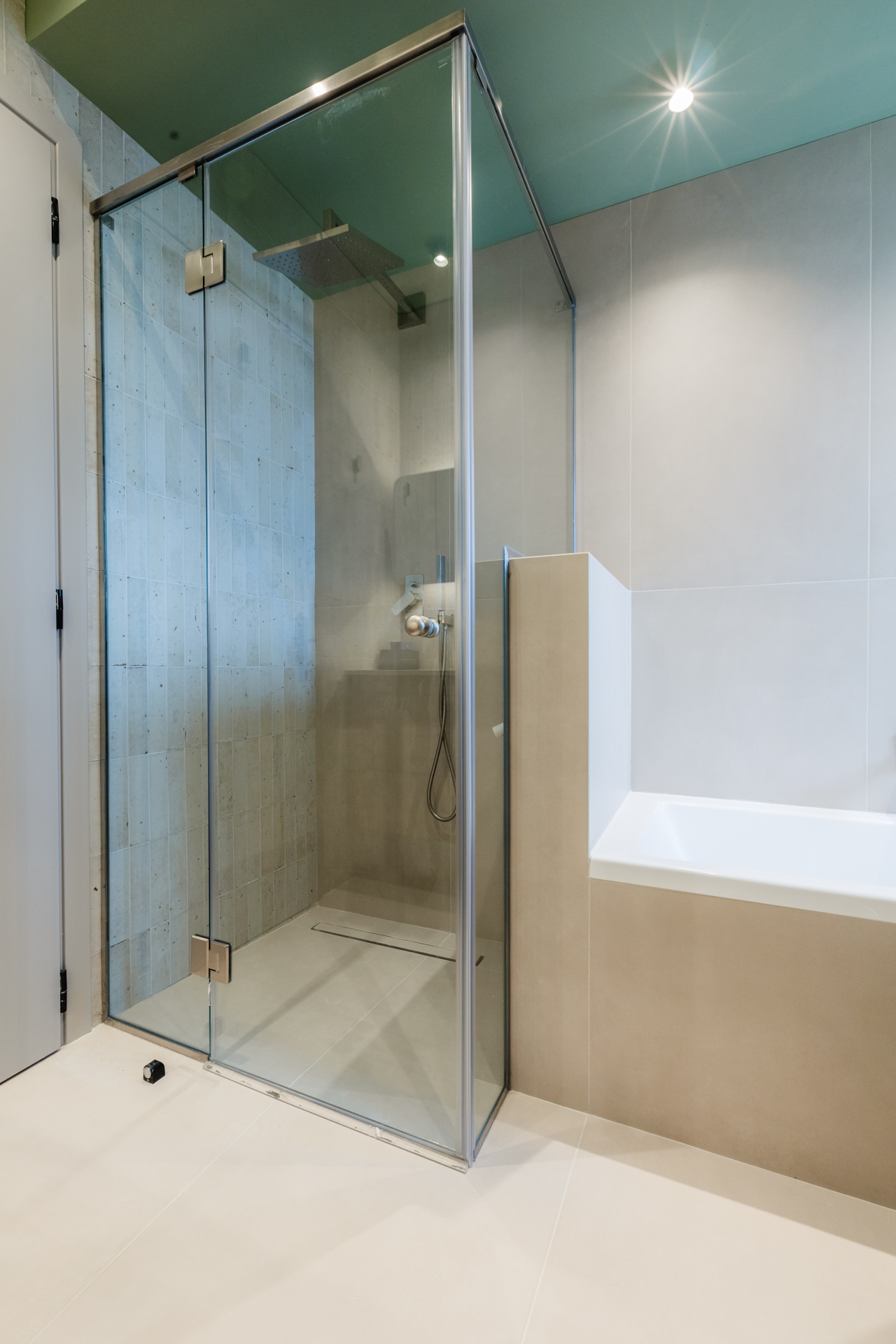 Μοντέρνο μπάνιο με ντουζιέρα και μπανιέρα Πράσινα εξαγωνικά πλακάκια μπάνιου Ξύλινο έπιπλο μπάνιου με fluted λεπτομέρειες Μπλε πλακάκια τοίχου μπάνιου Εντοιχισμένο καζανάκι και κρεμαστή λεκάνη Μοντέρνα καμπίνα ντους με διάφανο κρύσταλλο