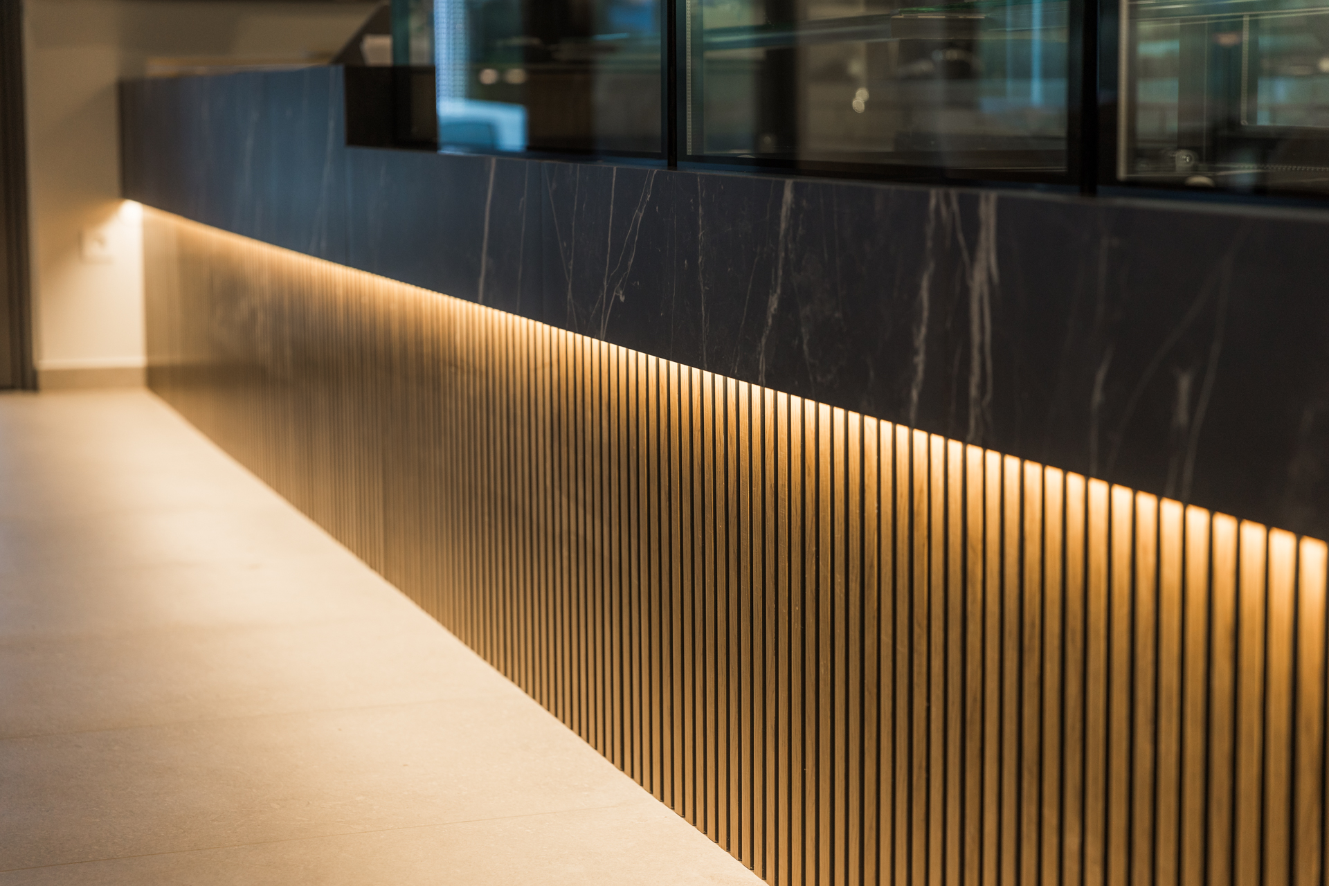 Εσωτερικός χώρος μοντέρνου καφέ με γκρι καθίσματα, ξύλινους τοίχους και πράσινη οροφή.