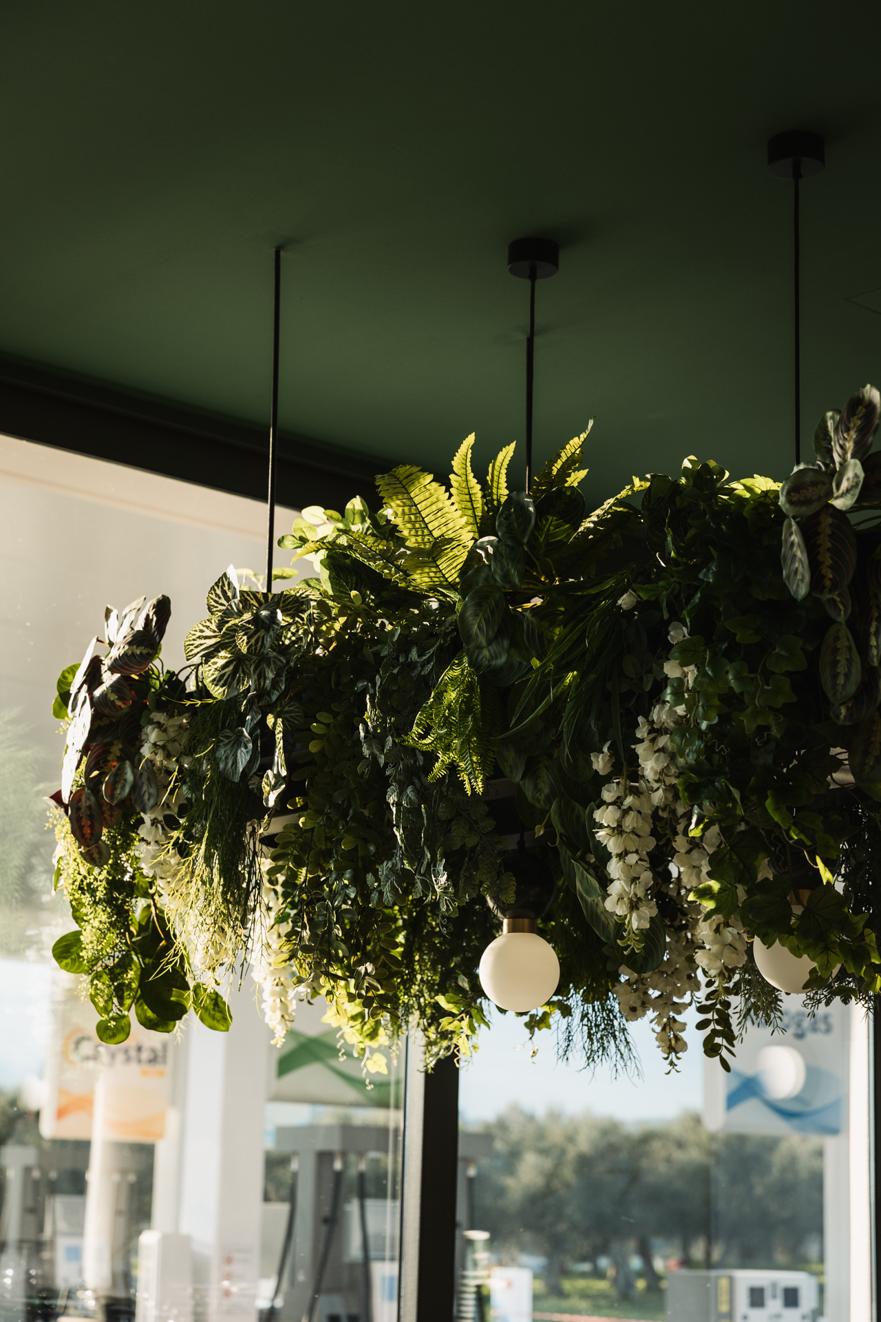 Εσωτερικός χώρος μοντέρνου καφέ με γκρι καθίσματα, ξύλινους τοίχους και πράσινη οροφή.