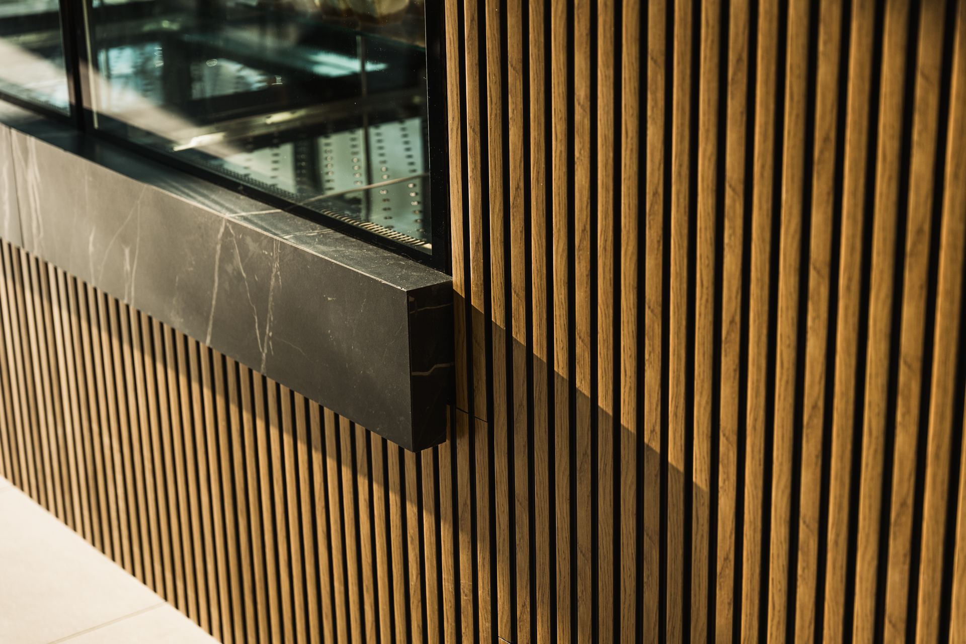 Εσωτερικός χώρος μοντέρνου καφέ με γκρι καθίσματα, ξύλινους τοίχους και πράσινη οροφή.