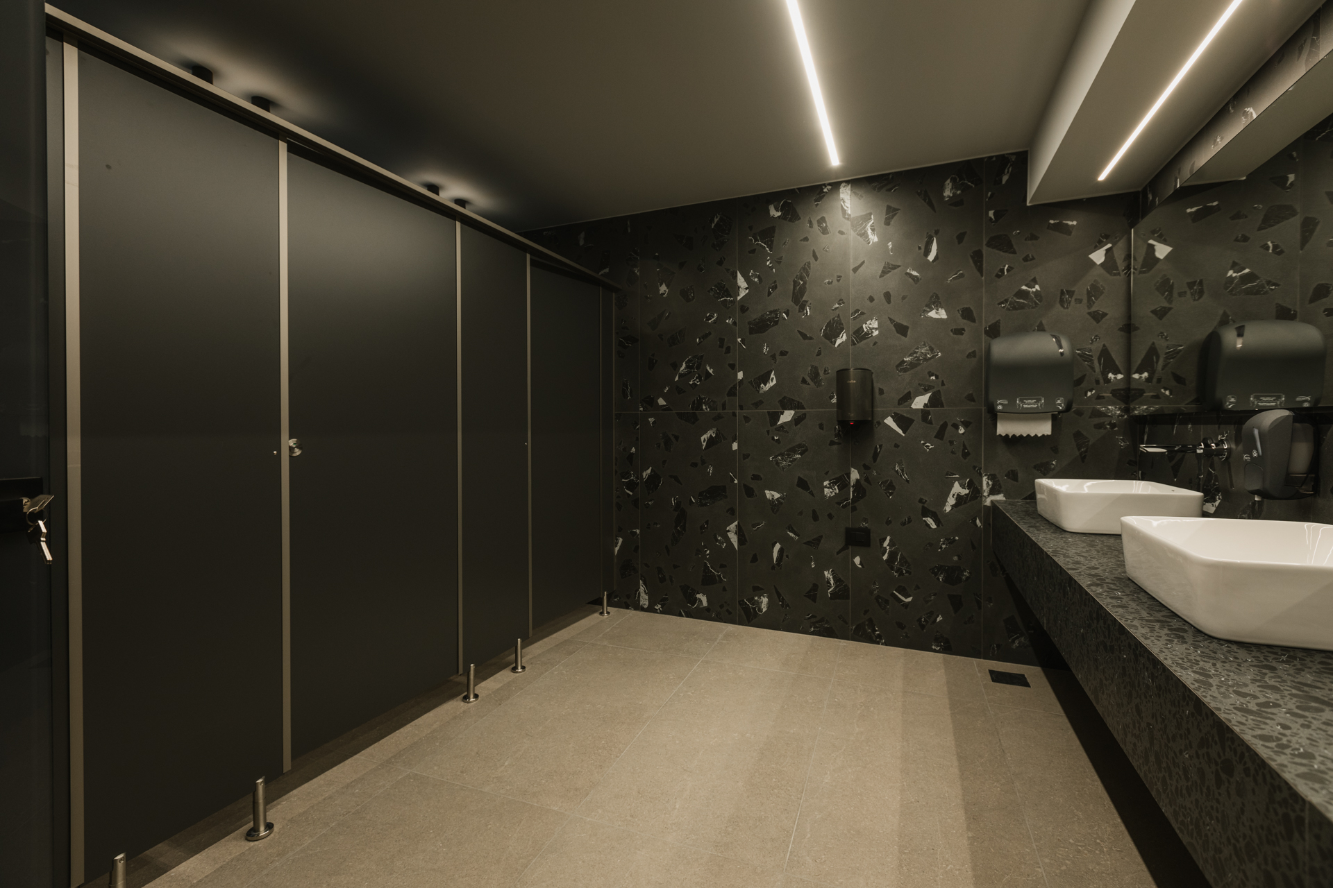 Εσωτερικός χώρος μοντέρνου καφέ με γκρι καθίσματα, ξύλινους τοίχους και πράσινη οροφή.