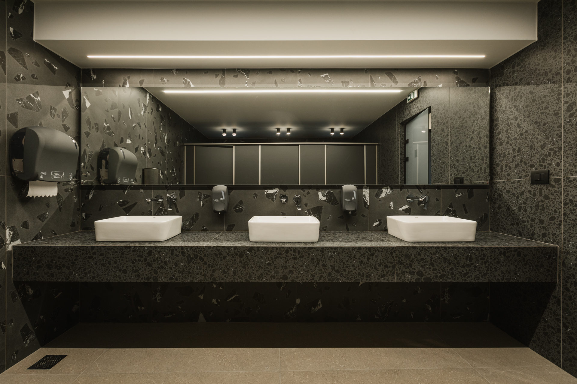 Εσωτερικός χώρος μοντέρνου καφέ με γκρι καθίσματα, ξύλινους τοίχους και πράσινη οροφή.