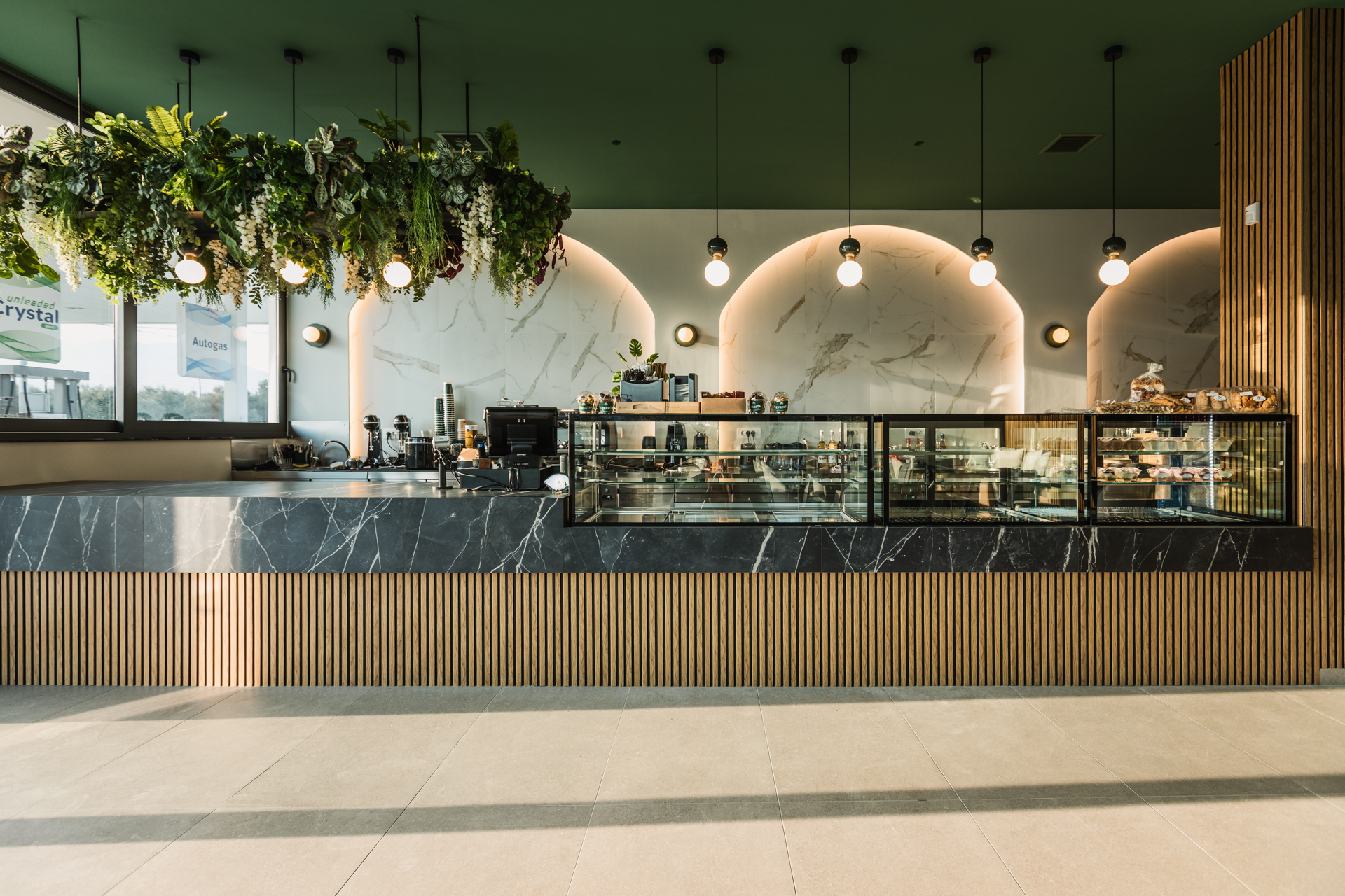 Εσωτερικός χώρος μοντέρνου καφέ με γκρι καθίσματα, ξύλινους τοίχους και πράσινη οροφή.