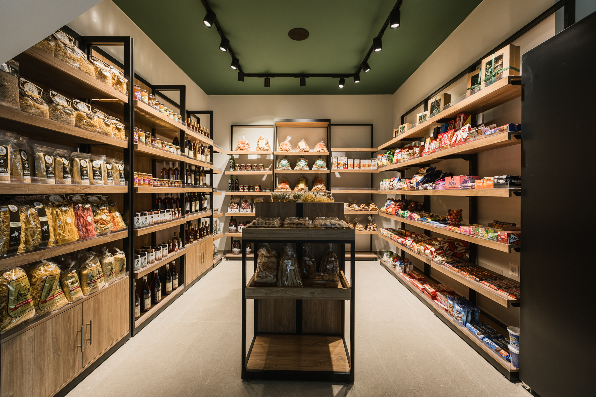 Εσωτερικός χώρος μοντέρνου καφέ με γκρι καθίσματα, ξύλινους τοίχους και πράσινη οροφή.