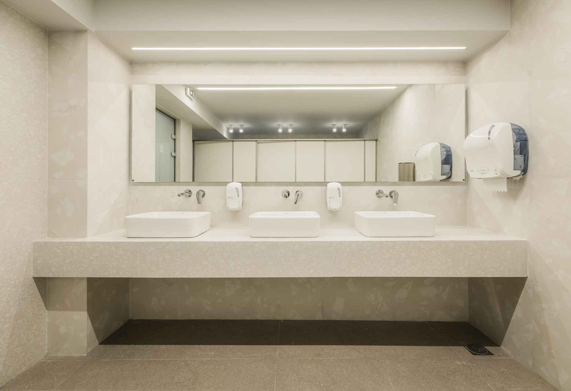 Εσωτερικός χώρος μοντέρνου καφέ με γκρι καθίσματα, ξύλινους τοίχους και πράσινη οροφή.